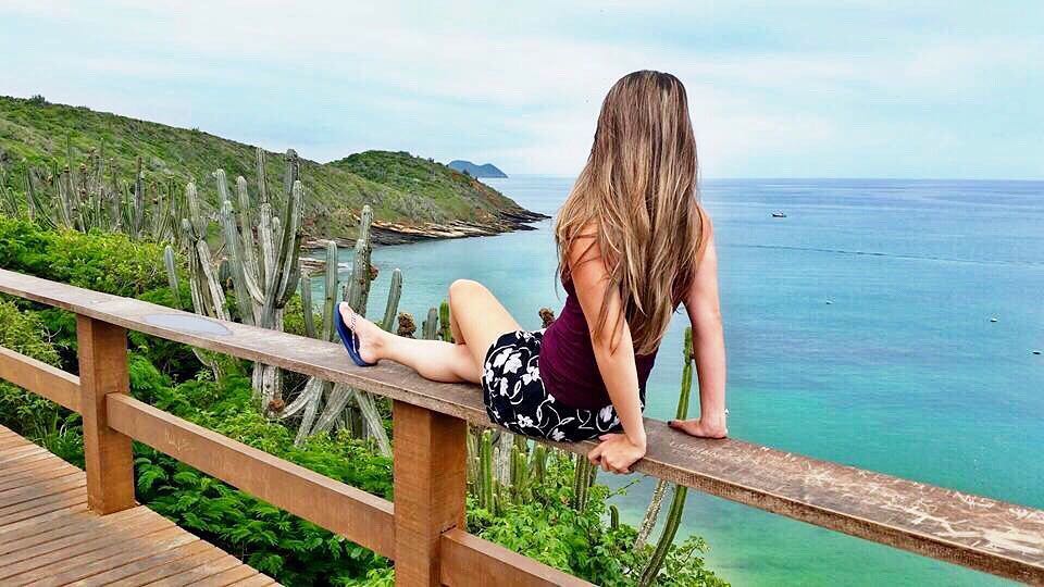 Turista tirando foto do mar azul-turquesa no Mirante de João Fernandes em Búzios