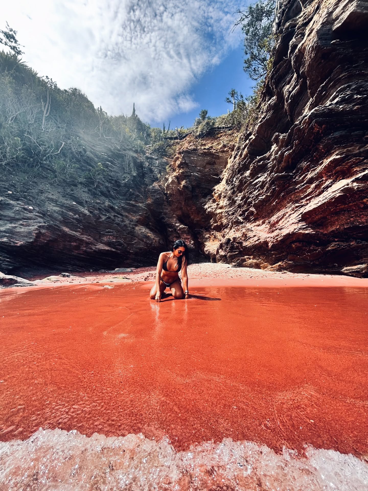 Close das areias rosadas da Praia do Forno em Búzios com água azul-turquesa ao fundo.