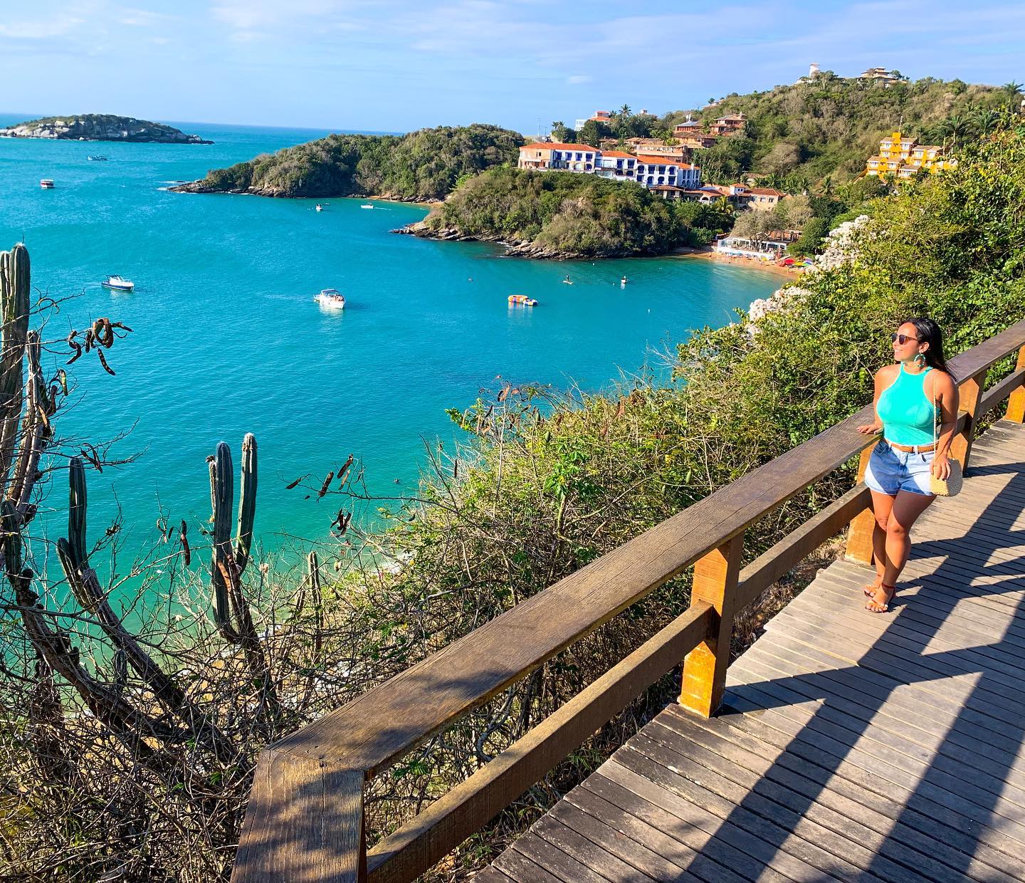 Una persona posando para una foto en un mirador acantilado de Búzios con un buggy privado y el mar azul brillante de fondo