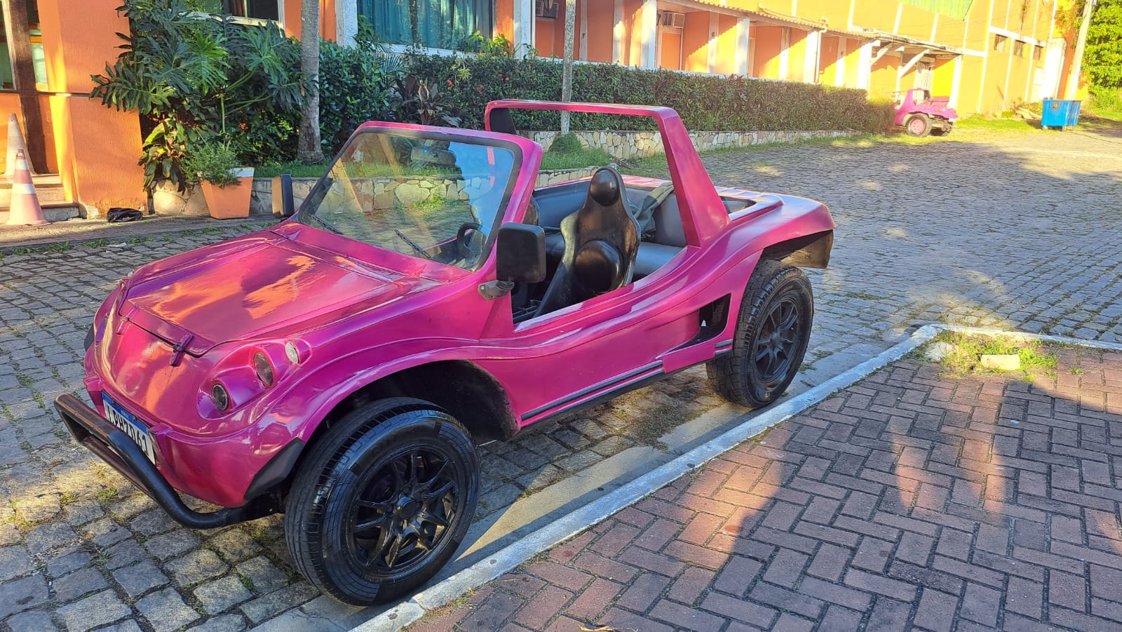 A pink open-air rental buggy parked near the coast in Búzios, offering a fun alternative to traditional car rentals.