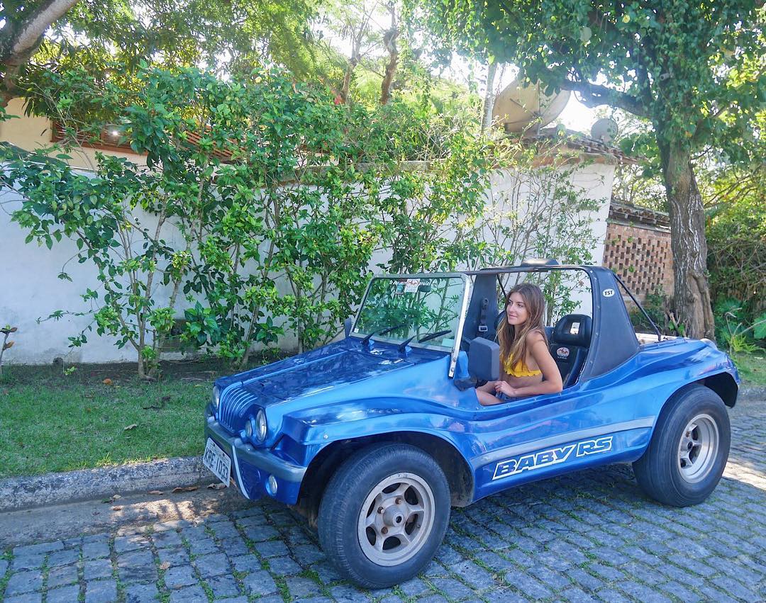 Turistas aproveitando o dia ensolarado de inverno em um buggy de passeio em Búzios com vista para o mar azul.