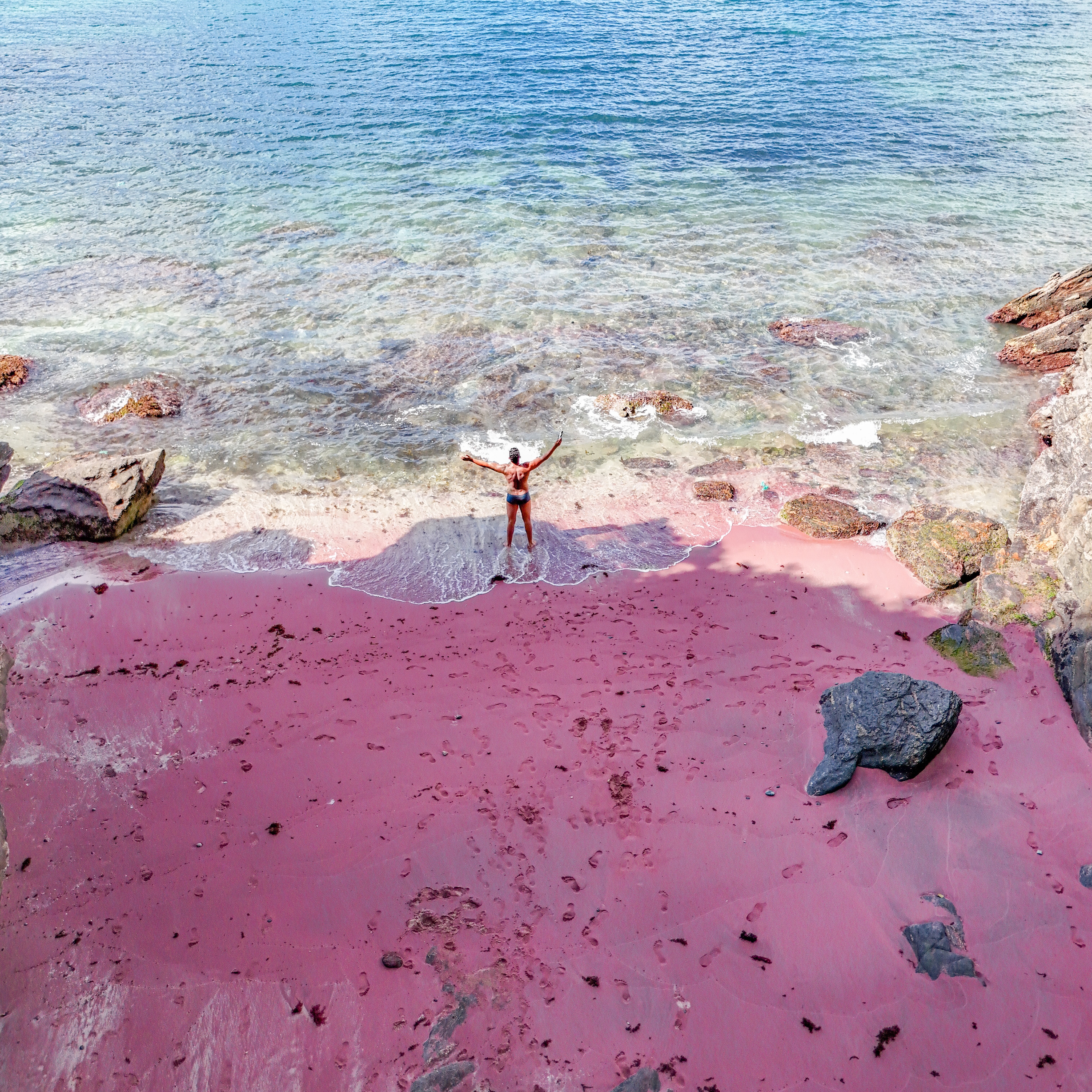 Panoramic view of the unique pink sand and clear turquoise water at Praia do Forno in Búzios.